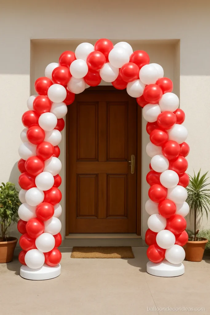 Balloon arch decoration over a home entrance in red and white spiral clusters