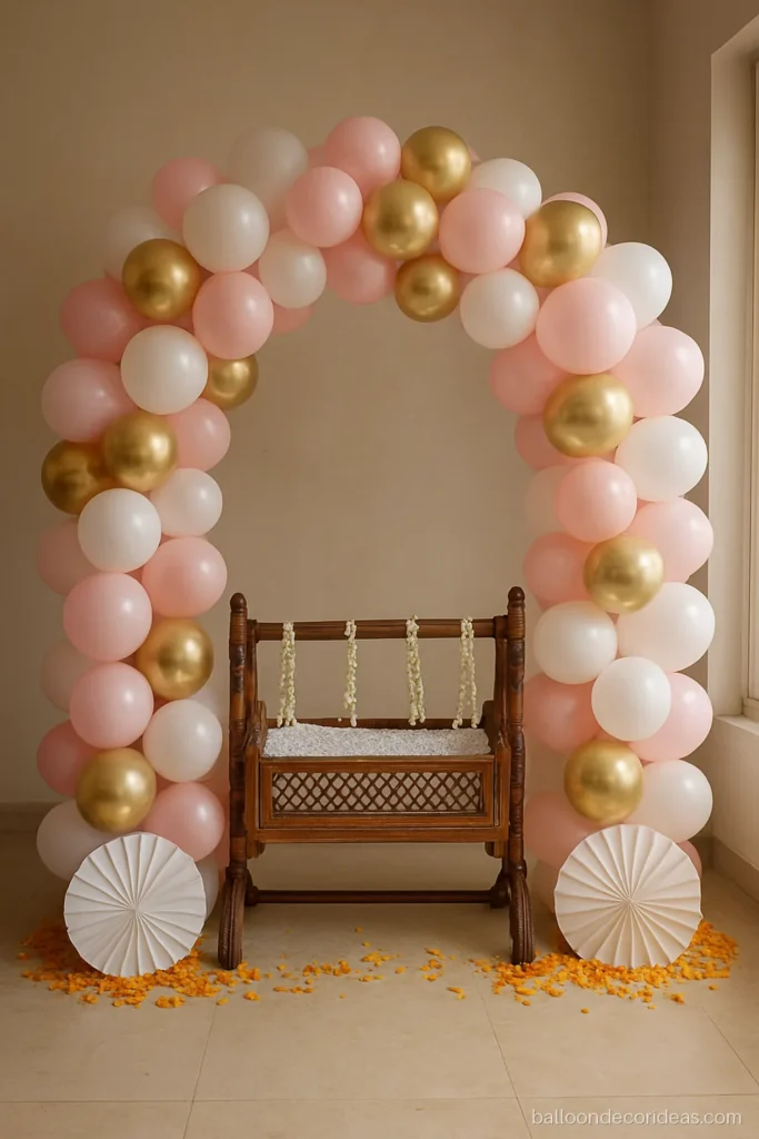 Balloon baby girl naming ceremony decoration with a pink and white arch over a cradle