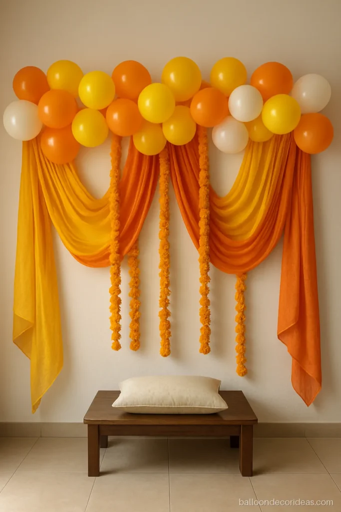 Backdrop balloon decoration with draped dupattas, marigolds and orange and yellow balloons