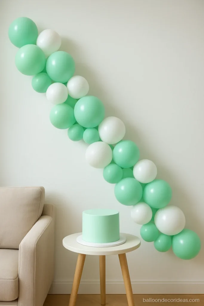 Simple birthday balloon decoration wall with a mint and white diagonal garland